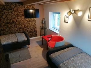 a room with two beds and a red chair at Zum Pfarrberg in Meerane