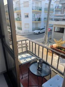 balcón con mesa y vistas a la calle en Sol & Surf, en Lourinhã