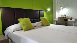 a large white bed with two lime green pillows at Huéspedes Sa Font in Ibiza Town