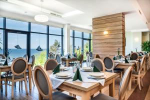 a restaurant with wooden tables and chairs and large windows at Sunset Spa in Rewal