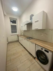 a kitchen with white cabinets and a washer at Hostel KASZUBSKA in Wrocław
