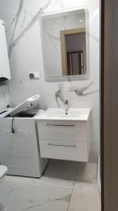 a white bathroom with a sink and a mirror at Apartament Muszelka in Łeba
