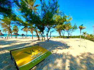 a sign on a beach with trees and the ocean at Vg Sun Cumbuco B2 105 in Cumbuco