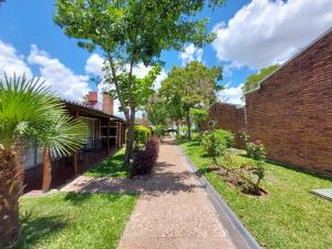 Una pasarela en un jardín junto a un edificio de ladrillo en Hotel Jardines de Dayman en Termas del Daymán