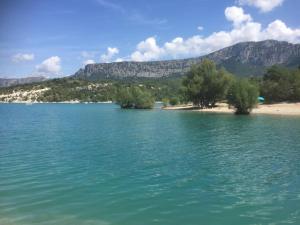 a body of water with a beach and mountains in the background at Maison individuelle, La Miloune in Le Val