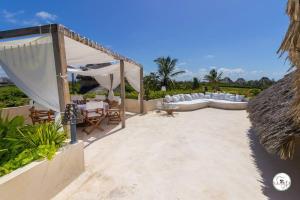 a patio with a couch and chairs and a tent at Baobab on the sand Apartment in Watamu