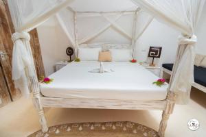 um quarto com uma cama de dossel branca em Baobab on the sand Apartment em Watamu