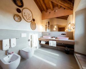uma casa de banho com 2 lavatórios, um WC e um espelho. em Conti Thun Wine Resort em Puegnago