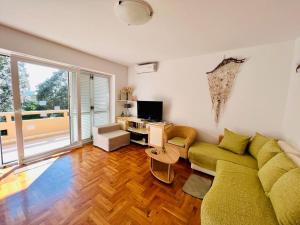 ein Wohnzimmer mit einem grünen Sofa und einem TV in der Unterkunft Novalja Lokvice in Novalja