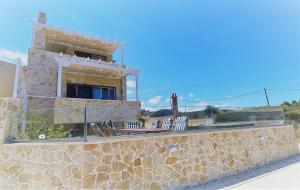 a building on a stone wall with a balcony at Villa Arkadia Seafront Villa Ai-Lagoudis Beach in Kyparissia