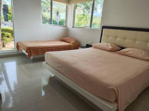 a bedroom with a large bed and two windows at Casa Campestre en Melgar in Melgar