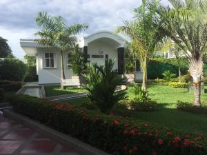 een wit huis met palmbomen en een tuin bij Casa Campestre en Melgar in Melgar
