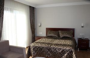 a bedroom with a bed and a chair and a window at Keyf Konak Boutique Hotel in Aydın