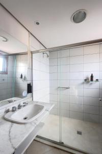 a bathroom with a sink and a glass shower at Flat Avenida Independência in Porto Alegre