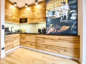kuchnia z drewnianymi szafkami i dużym obrazem na ścianie w obiekcie VisitZakopane - Tatra Ski Apartment w Zakopanem