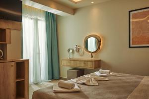 a bedroom with a bed with a mirror and a sink at Iniohos Zante Hotel & Suites in Argasi