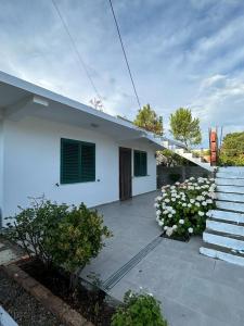 uma casa branca com escadas e flores em frente em Private House Velipoj em Velipojë