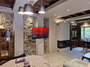 a living room with a tv on a stone wall at Filia Country House in Fília