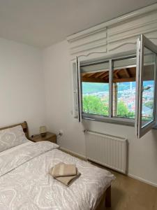 a white bedroom with a bed and a window at Mostar View House in Mostar