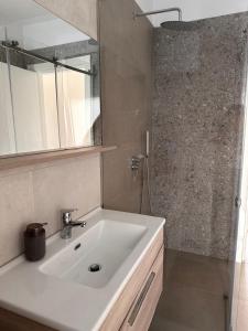 ein Badezimmer mit einem weißen Waschbecken und einer Dusche in der Unterkunft ByBreeze Appartments in Durrës