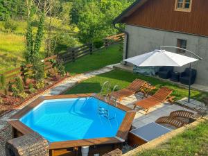 einen Blick über einen Pool mit 2 Stühlen und einem Sonnenschirm in der Unterkunft Kuća za odmor Zora 