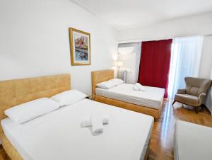 een hotelkamer met 2 bedden en een stoel bij Victroria Grand Palace Apartment in Athene