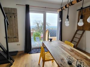 Dannenfels的住宿－Ferienloft Ottos Werkstatt mit Saunafass，一间带木桌和大窗户的用餐室