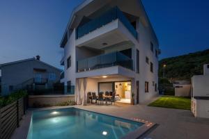 a house with a swimming pool in front of it at Luxury apartment Marco Polo with a private swimming pool with salt sea water in Punat