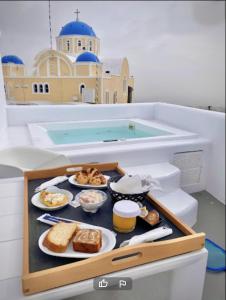 a tray of food on a table in front of a swimming pool at Eternity Suites Santorini in Fira