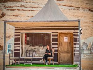 une femme assise sur une chaise dans une petite maison dans l'établissement Tower Rum Camb, à Wadi Rum
