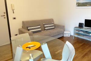 uma sala de estar com uma mesa de vidro e um sofá em La casa di Paola e Betti em Alba