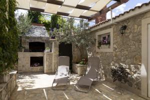 a patio with two chairs and a stone fireplace at M&T in Supetar