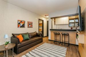 Una sala de estar con un sofá y una cocina. en WI-FI 500MB | Piscina | Sacada com Vista Mar #CA46, en Florianópolis