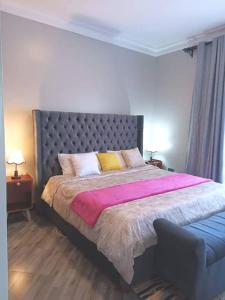 een slaapkamer met een groot bed en een blauwe bank bij Serene Homes 03 in Kampala