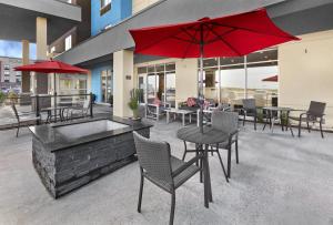un patio con mesas, sillas y una sombrilla roja en TownePlace Suites by Marriott Edmonton Sherwood Park, en Sherwood Park