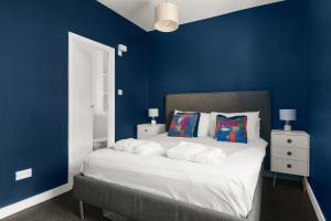 a blue bedroom with a large bed with blue walls at MyCityHaven - The Bathford Annexe in Bath