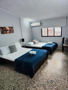 two beds in a room with blue sheets at Hotel Loft Dorado in Floridablanca