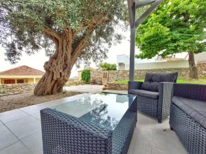 une terrasse avec une table et des chaises en verre ainsi qu'un arbre. dans l'établissement Calma Estate, à Elevtheraí