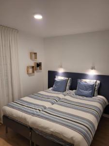 un grande letto con cuscini blu sopra di Vakantiehuis SARAH- vlakbij meer- van S&G Holiday a Nykroppa