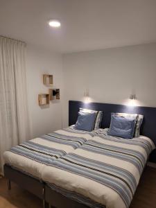a large bed with blue pillows on top of it at Vakantiehuis SARAH- vlakbij meer- van S&G Holiday in Nykroppa