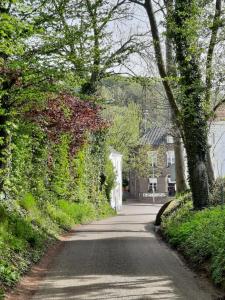 a winding road with ivy covered buildings and trees at Anno 1877 appartement met tuin in Slenaken