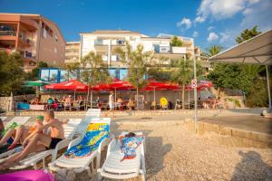 a group of people sitting on lounge chairs at a swimming pool at AG Komarna - Peljesac Bridge Apartments in Komarna