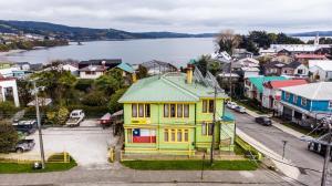 a yellow house with a green roof in a city at 13 Lunas Hostel in Ancud