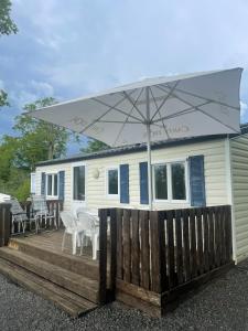 a mobile home with an umbrella on a wooden deck at Maison de 3 chambres avec piscine partagee terrasse amenagee et wifi a Argences en Aubrac in Banes