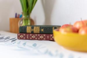 dois livros sentados numa mesa com uma tigela de maçãs em Nordic style room in a quiet residential area em Edimburgo