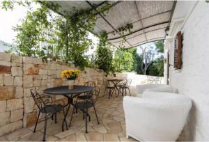 a patio with a table and chairs and a stone wall at Bed & Breakfast da Fabio e Paola in Ostuni