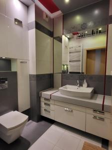 La salle de bains est pourvue de toilettes blanches et d'un lavabo. dans l'établissement PokornaM1, à Varsovie