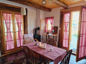 uma sala de jantar com mesa, cadeiras e janelas em Kuća za odmor Matovilka em Križevci