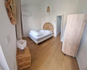 Habitación pequeña con cama y suelo de madera. en maison de village en Saint-Laurent-de-Carnols
