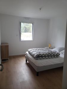een witte slaapkamer met een bed en een raam bij LA POINTE DE SEL in Fouesnant